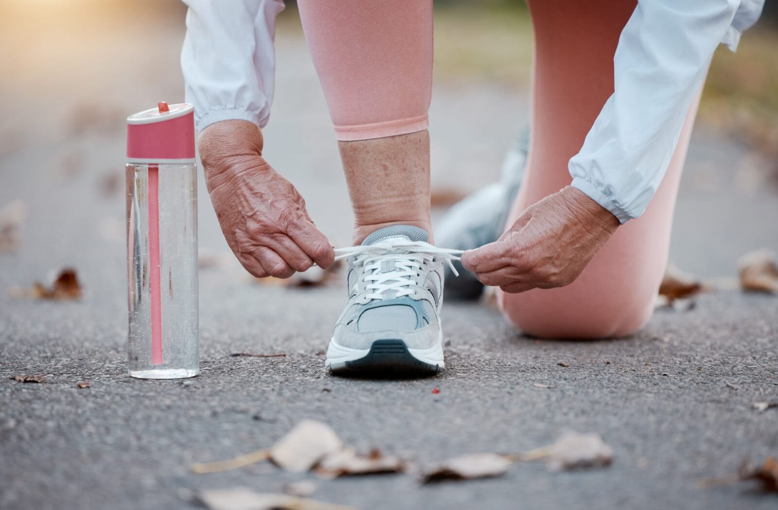 A close-up image of a senior lacing up their walking shoes for a safe, comfortable walk.