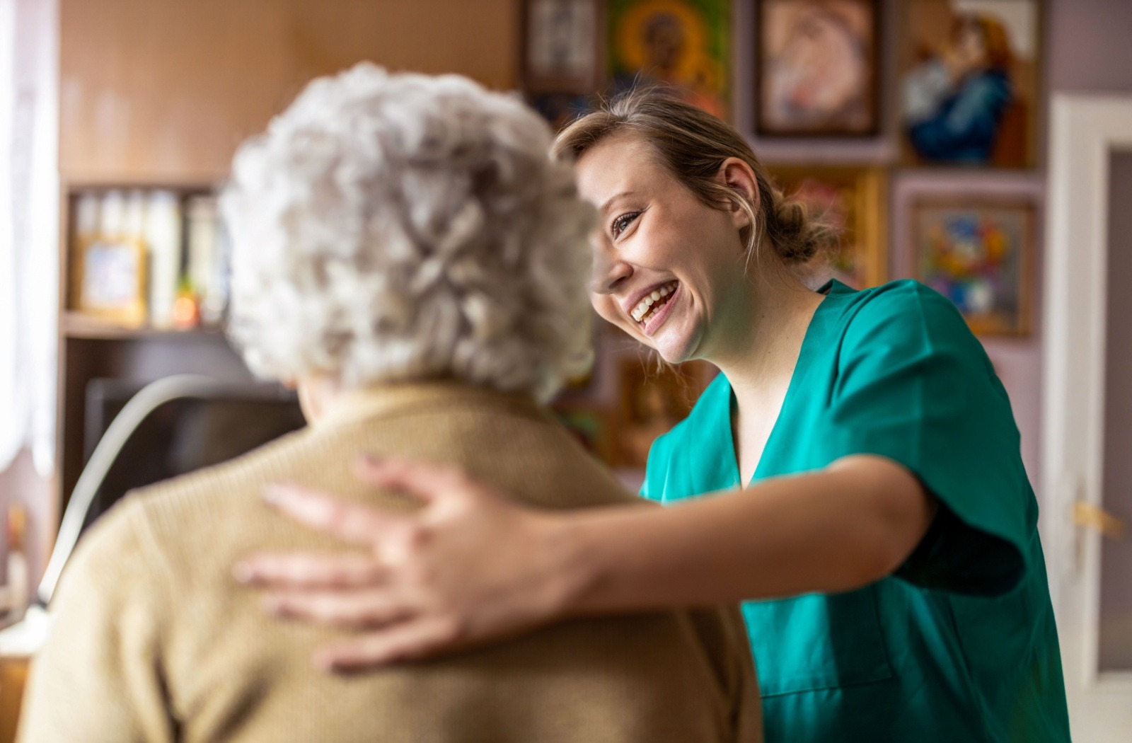 A caregiver in a senior living community puts their arm around an older resident and smiles