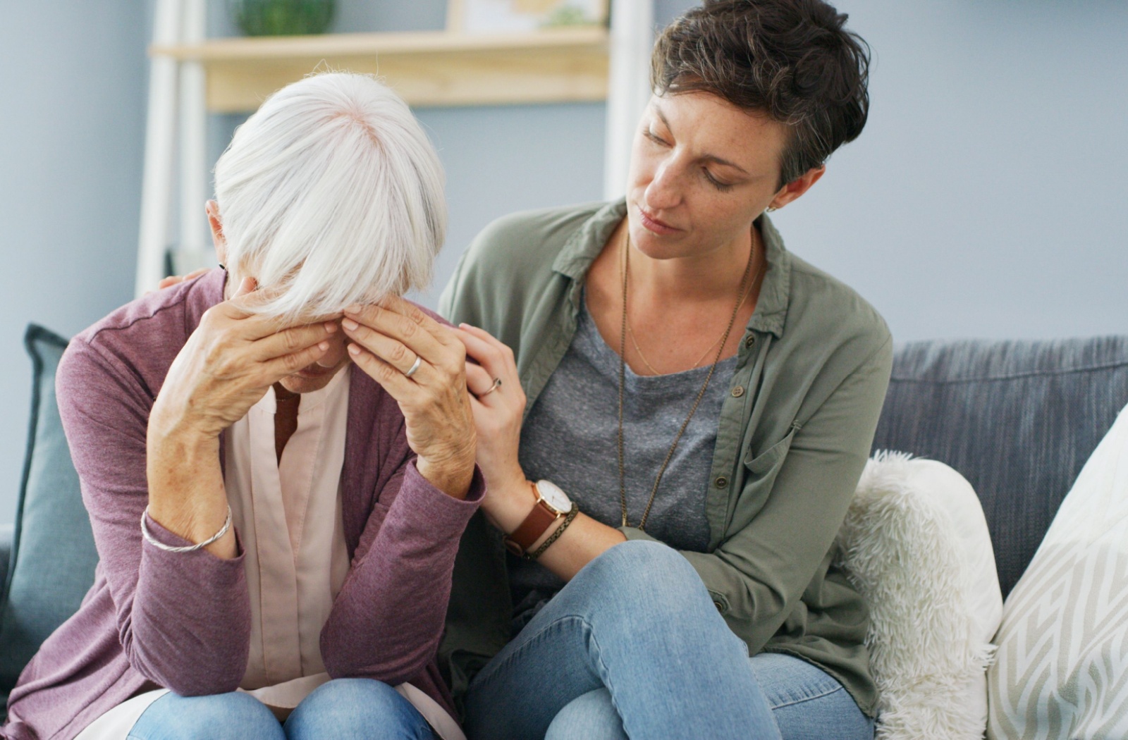 An adult child comforts their senior parent who is frustrated at experiencing difficulty remembering.