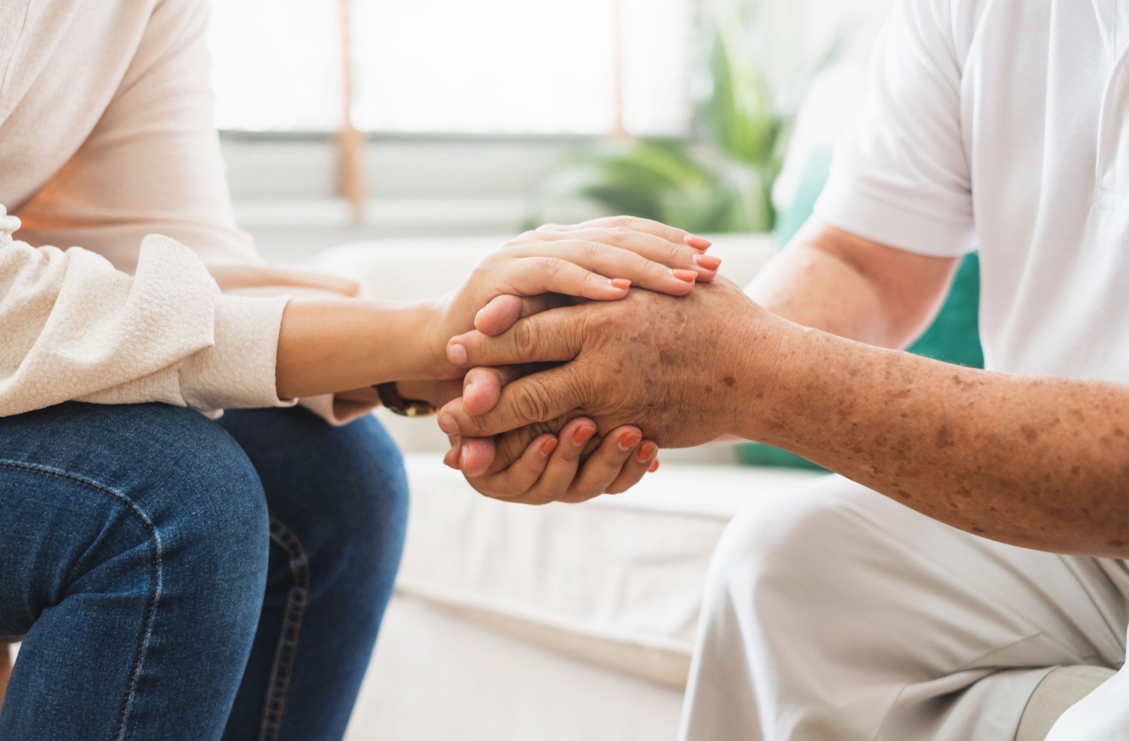A caregiver clasps hands with a senior loved one.
